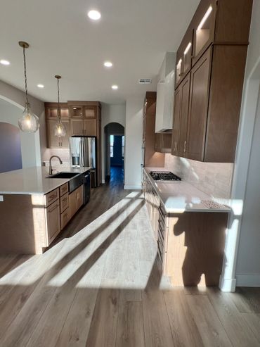 Modern kitchen with wooden cabinets and island under natural light.