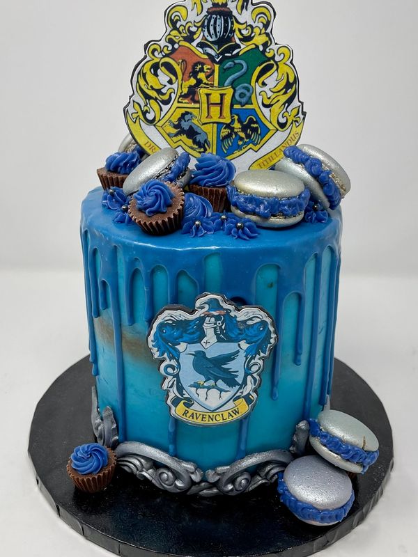 Ravenclaw blue cake with blue drip accented with Reeses peanut butter cups and silver macarons.