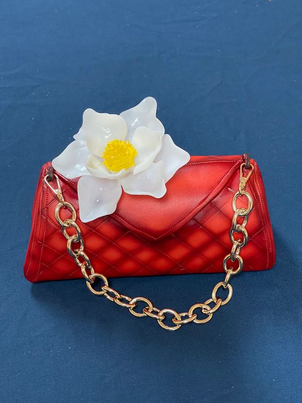 Red purse cake with white flower.