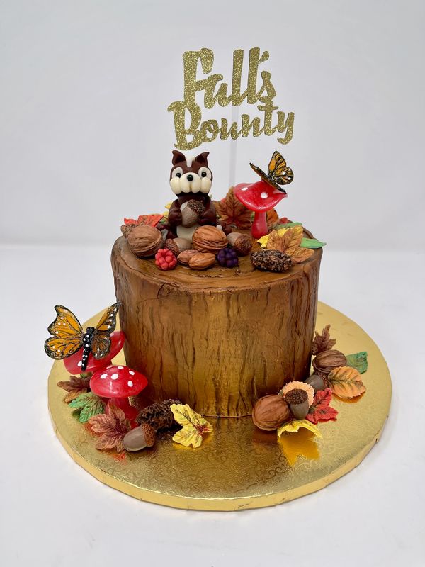 Stump cake with squirrel surrounded by  nuts, leaves mushrooms and butterflies.