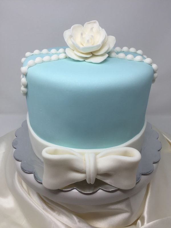 light blue cake white pearls and white rose on top white bow border