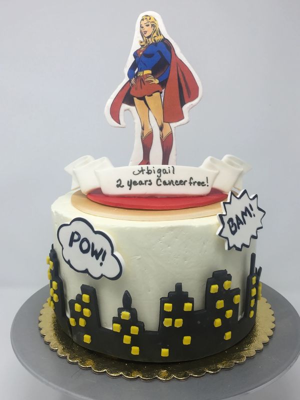 white cake black city scape on side Wonder Woman on top