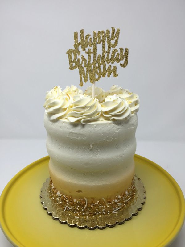 white cake airbrushed bottom border in gold with sprinkles, white rosettes on top
