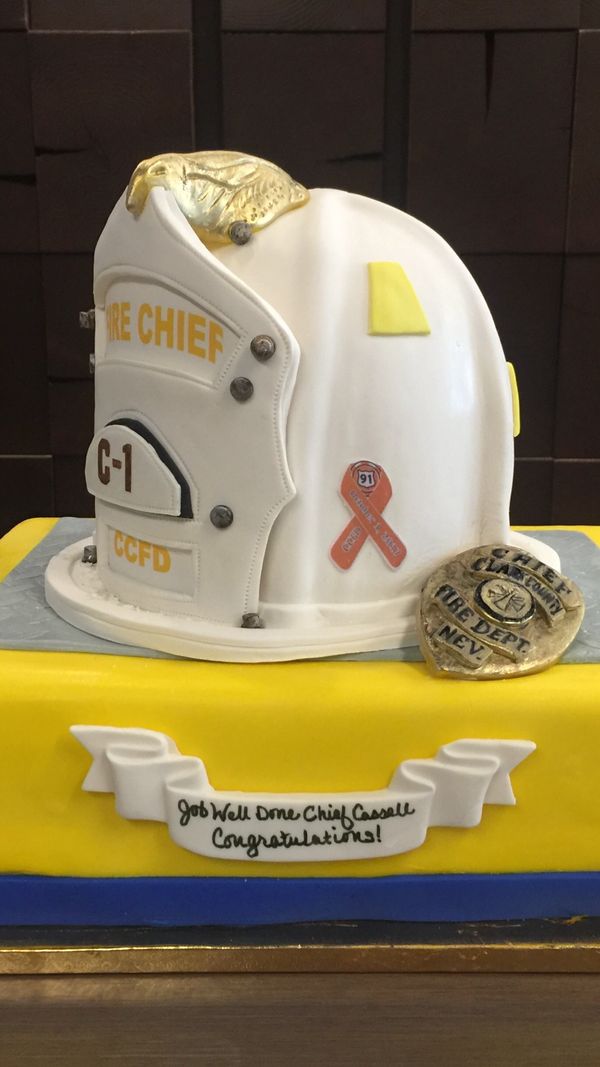 Fire Chief's Helmet and gold badge on top of a yellow cake with a blue border 