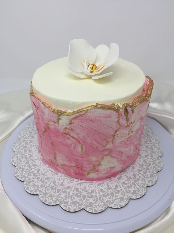 pink and white cake with white orchid on top