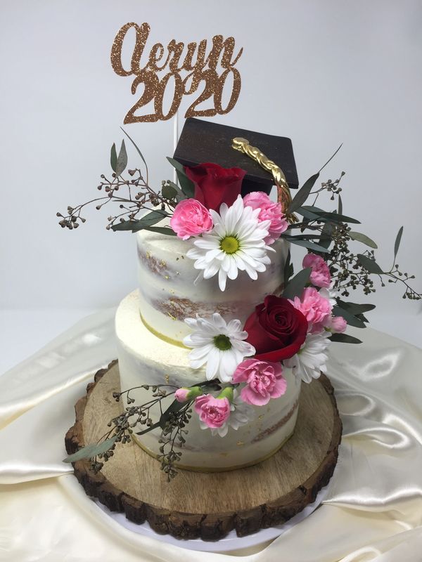 White naked cake with fresh flowers and black graduation cap