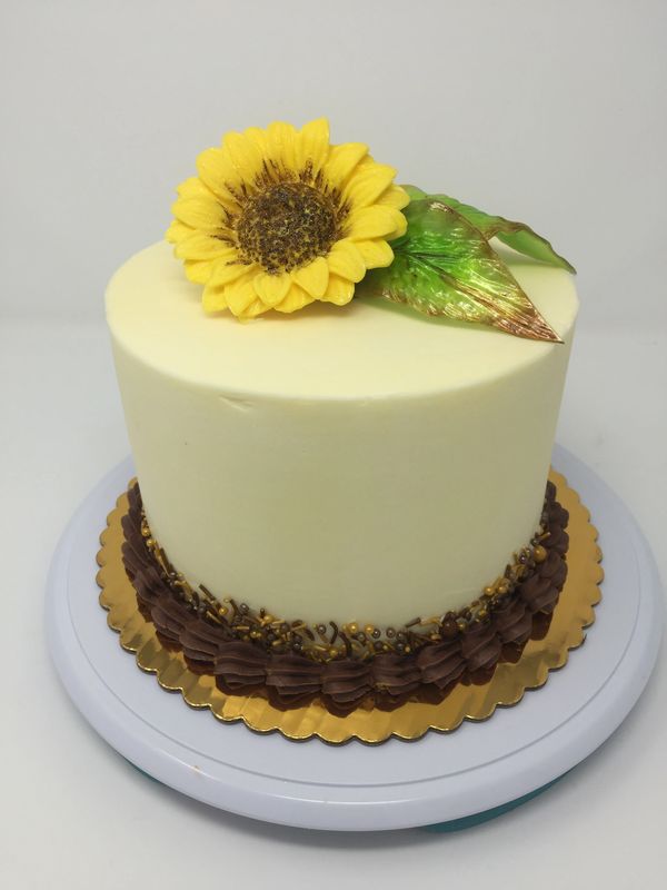white cake with yellow sunflower and green leaves on