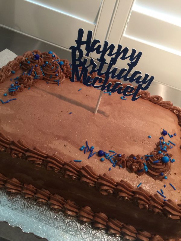 brown cake with brown rosettes on top and blue sprinkles