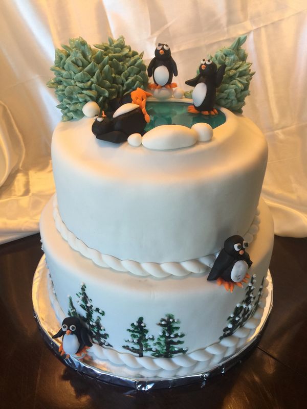 2 tier white cake with Christmas trees and penguins skating on top 