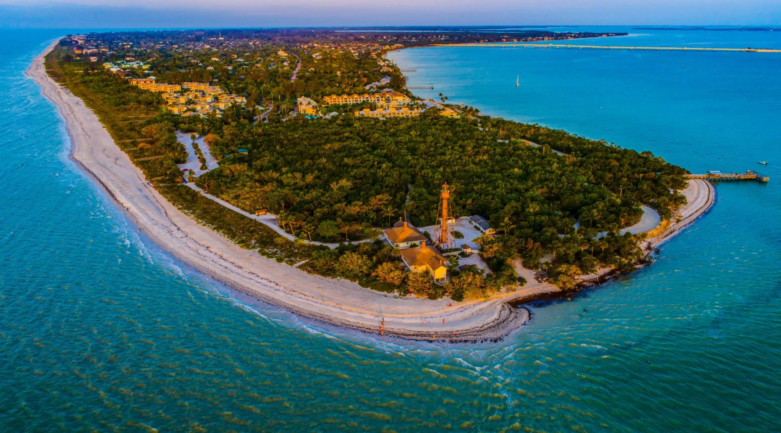 Aerial view of a coastal town with a lighthouse at the tip of a peninsula.