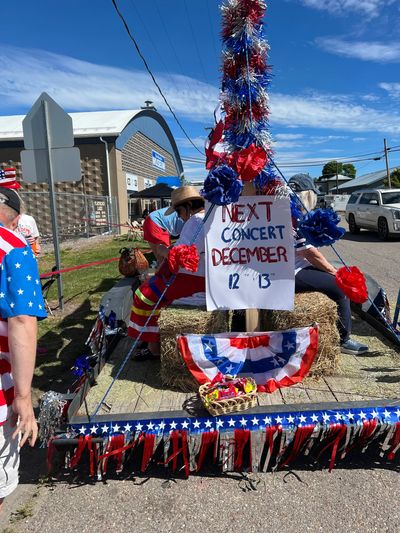 Patriotic parade float with concert sign and decorations.