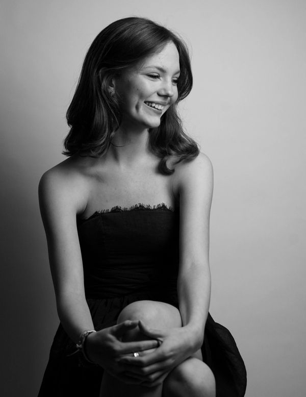 Black and white portrait of a smiling young woman in a strapless dress.