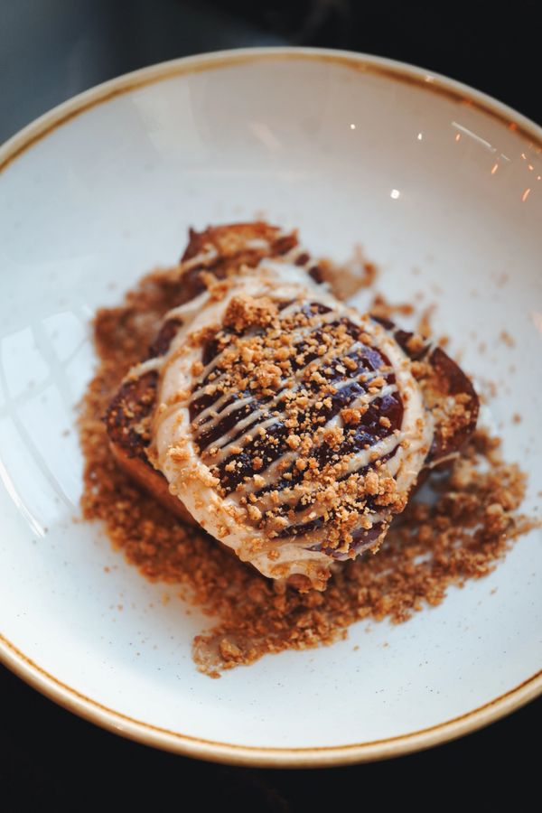A decadent dessert with chocolate and crumb topping on a white plate.