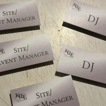 Name tags for Site/Event Manager and DJ roles on a scratched surface.