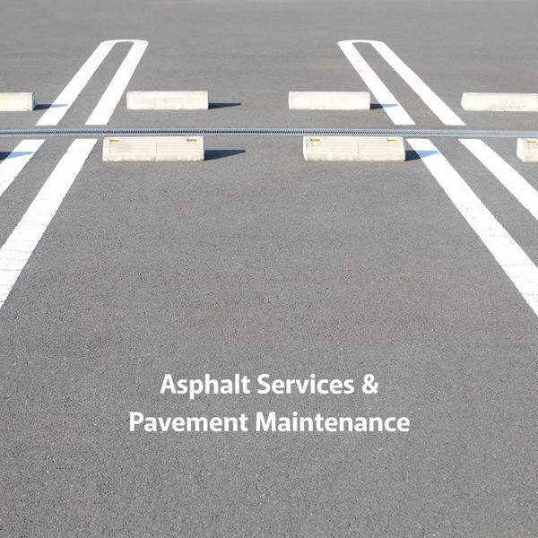 Empty parking spaces with clear white lines and text about asphalt and pavement services.