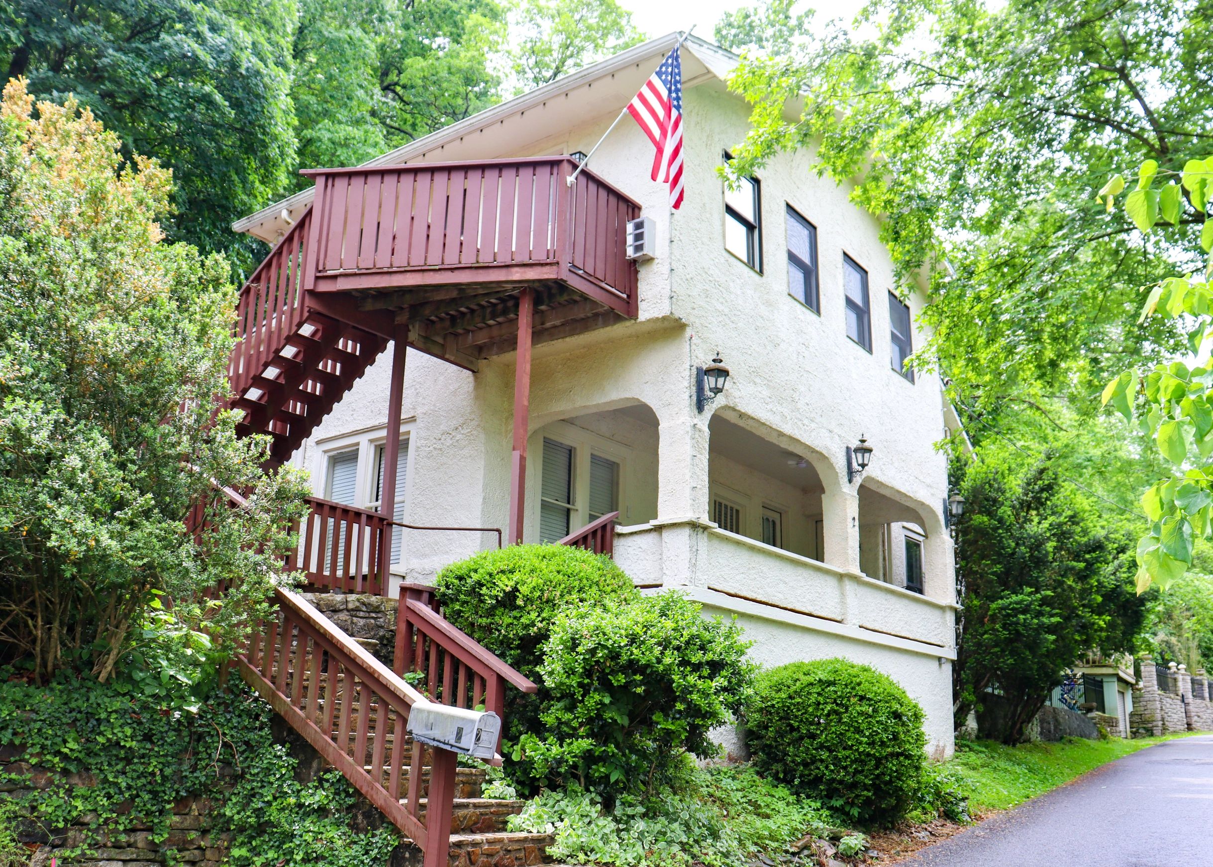Two-story house with a wooden balcony and American flag.