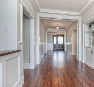 Elegant hallway with wooden flooring and white wainscoting.