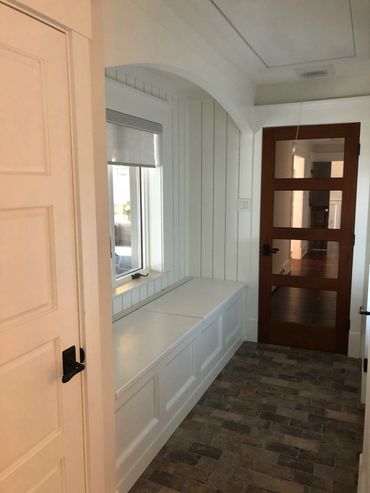 Cozy hallway with a white built-in bench and wooden door.