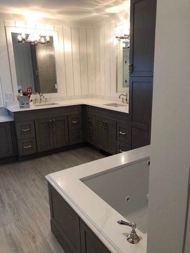 Modern bathroom with dark wood cabinets and white countertops.