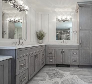 Modern bathroom with gray cabinetry and dual sinks under large mirrors.