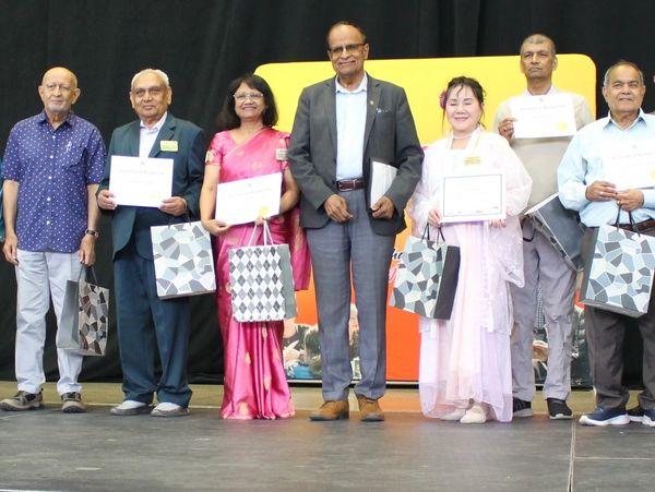 Group of six people holding certificates and gift bags.
