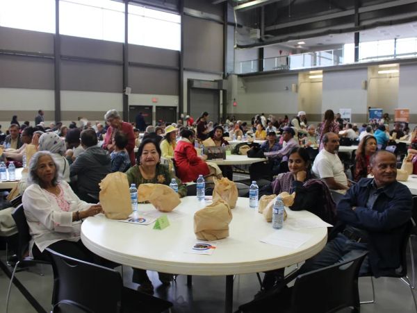 People gathered at a large indoor event sitting around tables.