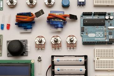 Various electronic components including an Arduino board, sensors, and batteries arranged neatly.