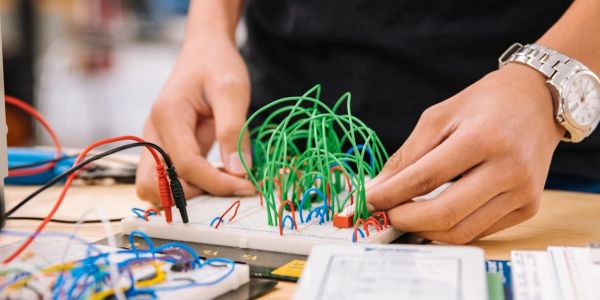 Person working on an electronic breadboard with wires and components.