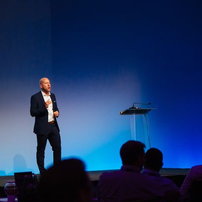 Man in suit giving a presentation on stage.
