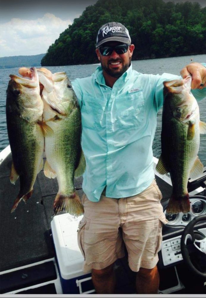 A fishermen holding 3 largemouth bass