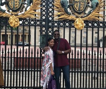 Couple posing in front of ornate iron gate.