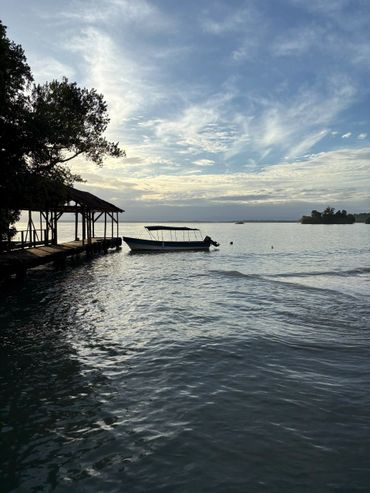 Boat docked near a wooden pier under a cloudy sky at dusk.