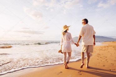 Couple walking hand-in-hand on a sunny beach at sunset.