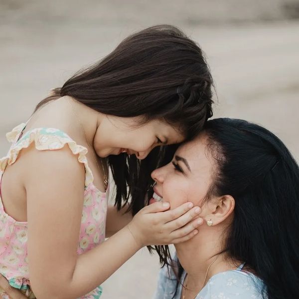 Young daughter holding mothers face lovingly while both are smiling