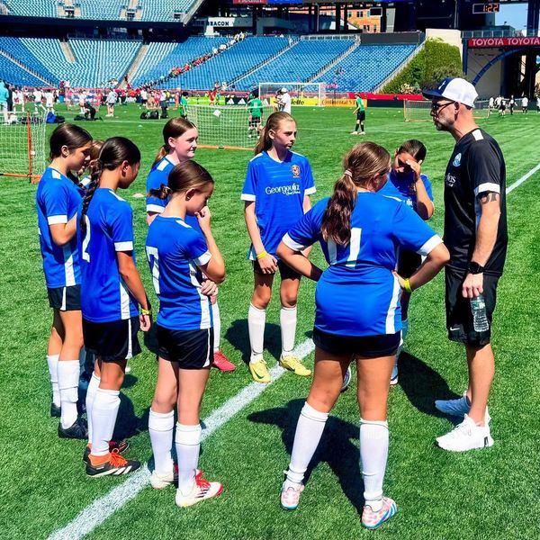 Youth soccer team listens attentively to coach during a field break.