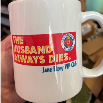 white coffee mug with The Husband Always Dies in pink