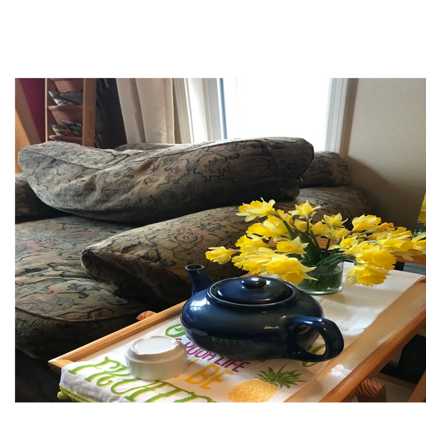 writing chair with blue teapot and yellow spring daffodils on a side table in jane's writing studio