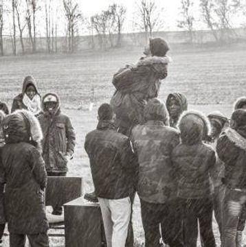A group of people in winter clothing gathered outdoors in snowfall.