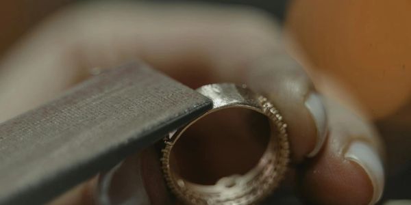 Hands filing a metal ring.