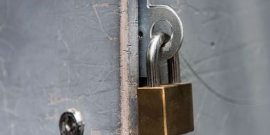 Close-up of a brass padlock securing a gray metal door.