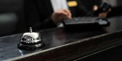 A service bell on a dark wooden reception desk with a blurred receptionist in the background.