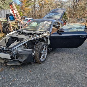 A partially disassembled black sports car with open door and exposed front.