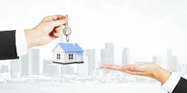 Hand giving house keys to another hand with city background.