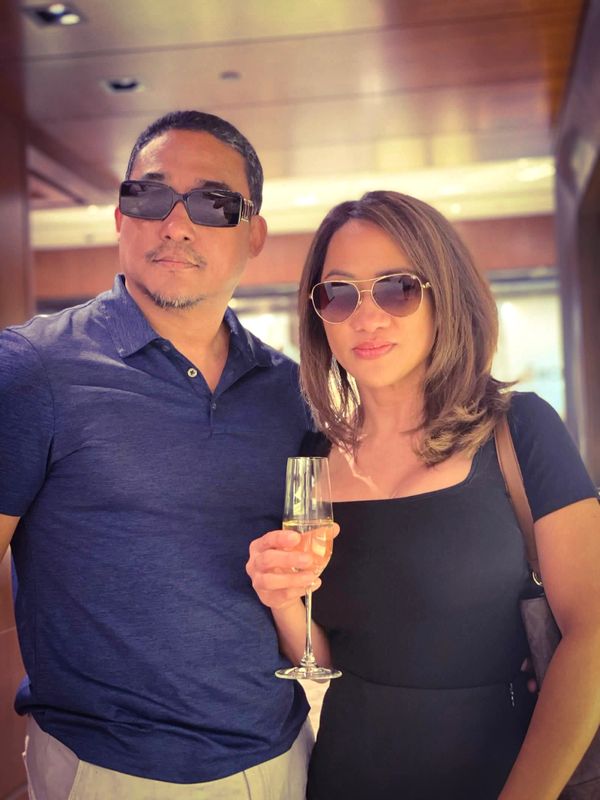 A stylish couple wearing sunglasses, enjoying a drink indoors.