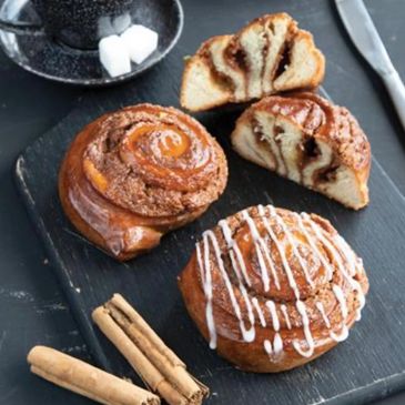 Freshly baked cinnamon buns drizzled with frosting.