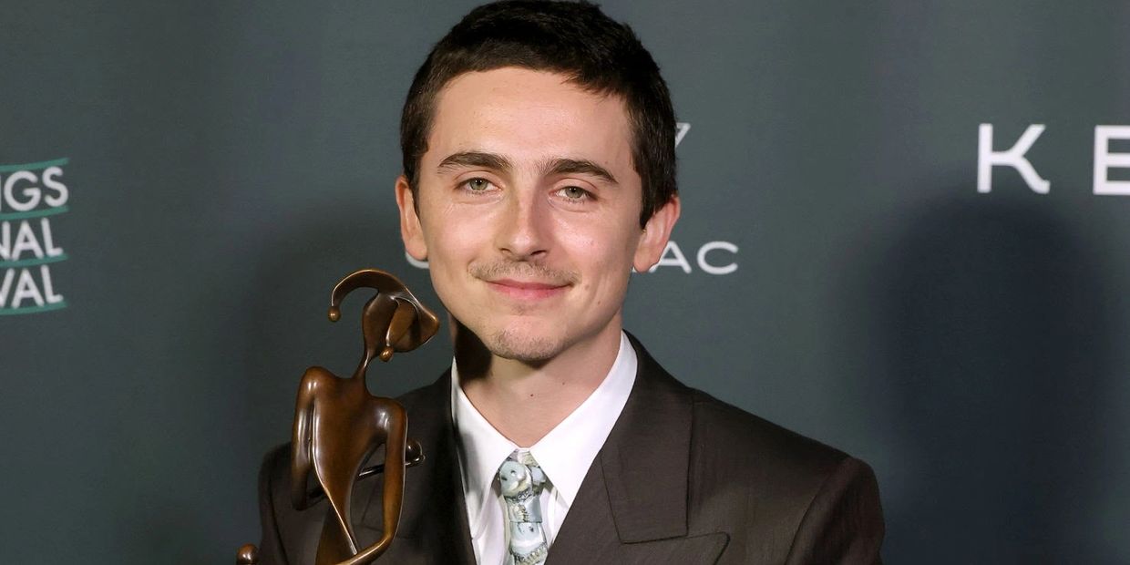 A man in a suit holds a Palm Springs International Film Festival award.
