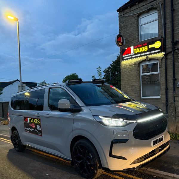 Taxi van parked near a taxi service office in evening light.