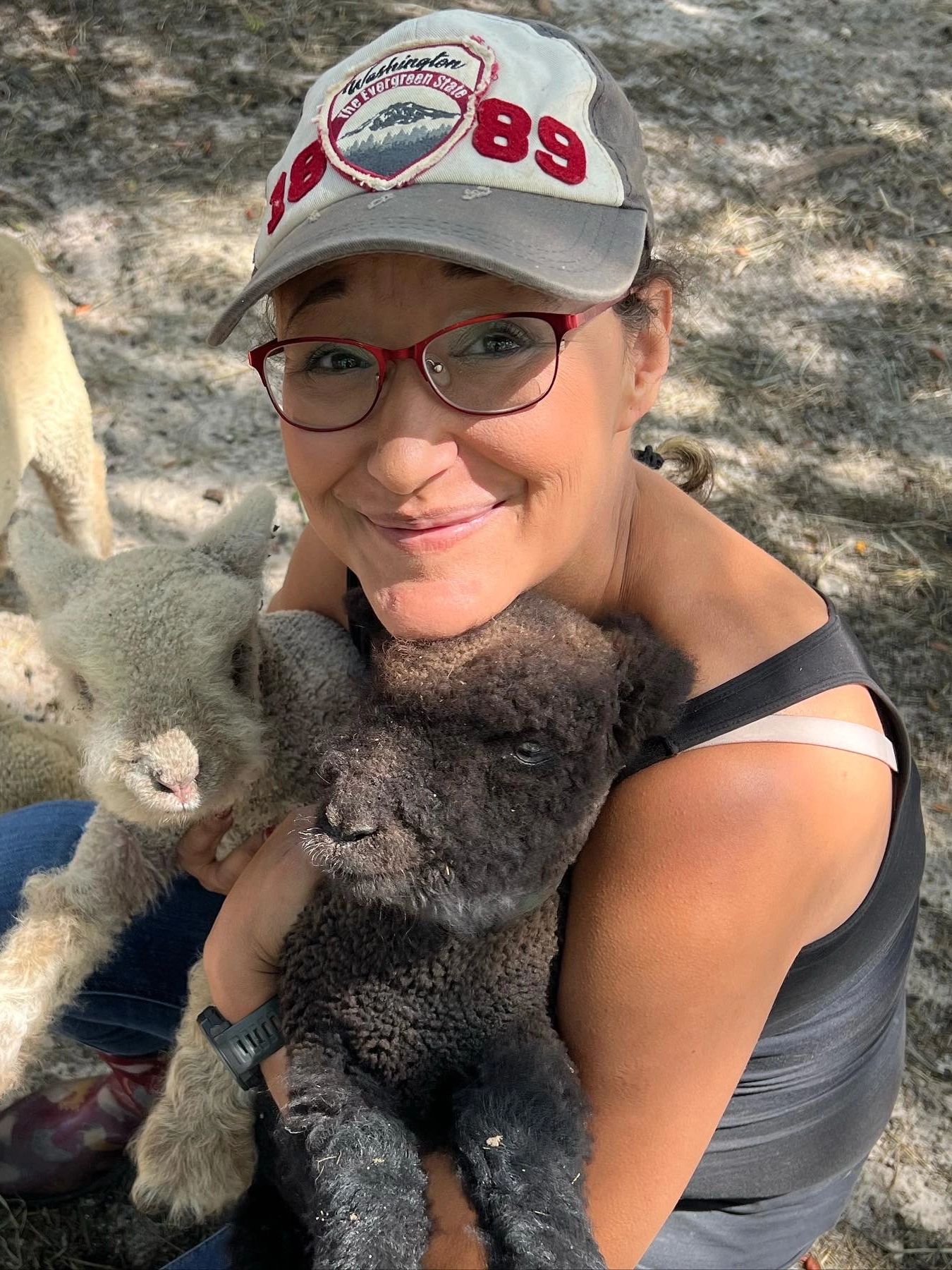 Carrie holding her 2 sheep and smiling. 