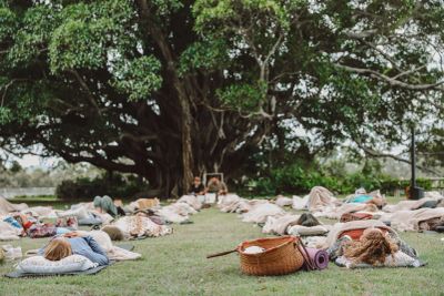 People lying on the grass in a peaceful outdoor setting under a large tree.