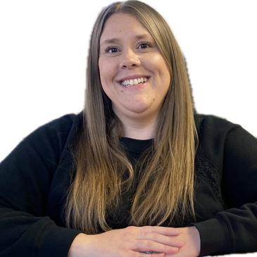 Smiling woman with long hair wearing a black top, sitting with hands folded.